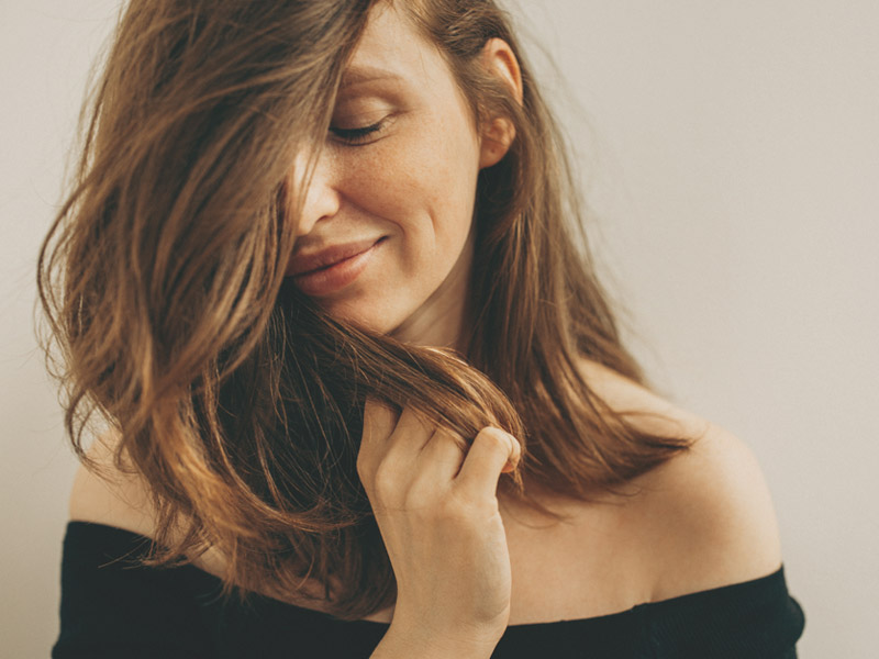 woman holding hair and looking down